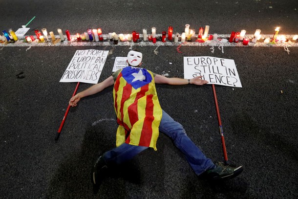 A man lays down on the ground with an Estelada (Catalan separatist flag) next to candles during a pr