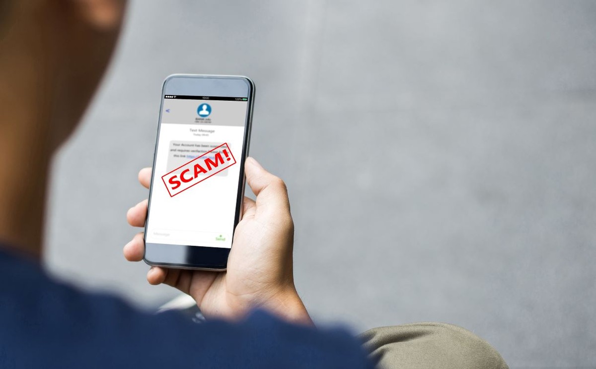 Mężczyzna trzymający w dłoni telefon z napisem scam