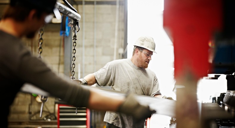 Steel workers placing sheet steel in a large brake pressThomas Barwick/Getty Images