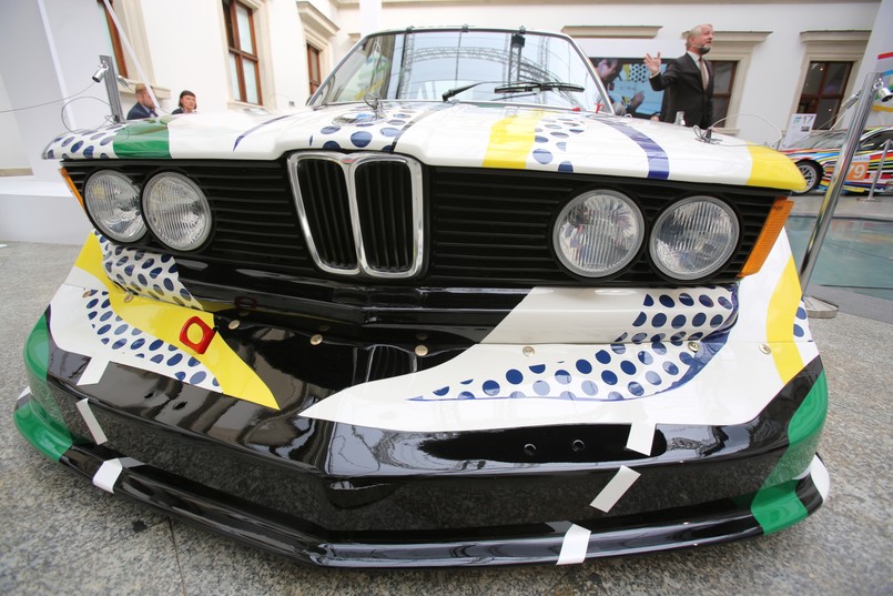 BMW 320i, samochód wyścigowy grupy 5. Silnik rzędowy, 4-cylindrowy o pojemność 2 l produkował 300 KM. Prędkość maksymalna - 257 km/h. Art Car projektu Roya Lichtensteina miał aż dwie premiery: jako dzieło sztuki został zaprezentowany w Centrum Pompidou w Paryżu, z kolei jako samochód wyścigowy wziął udział w wyścigu 24h Le Mans w czerwcu 1977 roku. Samochód prowadzili Francuzi Hervé Poulain i Marcel Mignot. Auto z numerem 50 wygrało w swojej klasie i zdobyło dziewiąte miejsce w klasyfikacji generalnej.