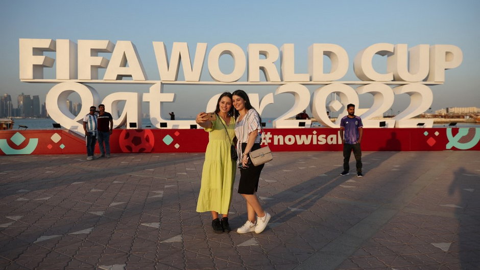 Ludzie robią sobie pamiątkowe zdjęcia z napisem Mistrzostw Świata FIFA w Doha