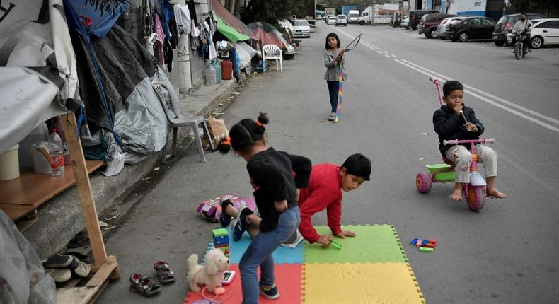 Children play near their families' tents set up on a street outside Eleonas refugee camp in Athens