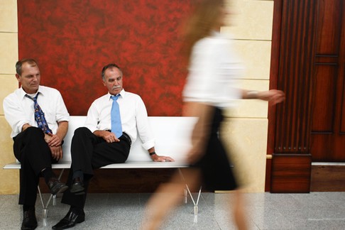 Two businessmen looking at woman's legs