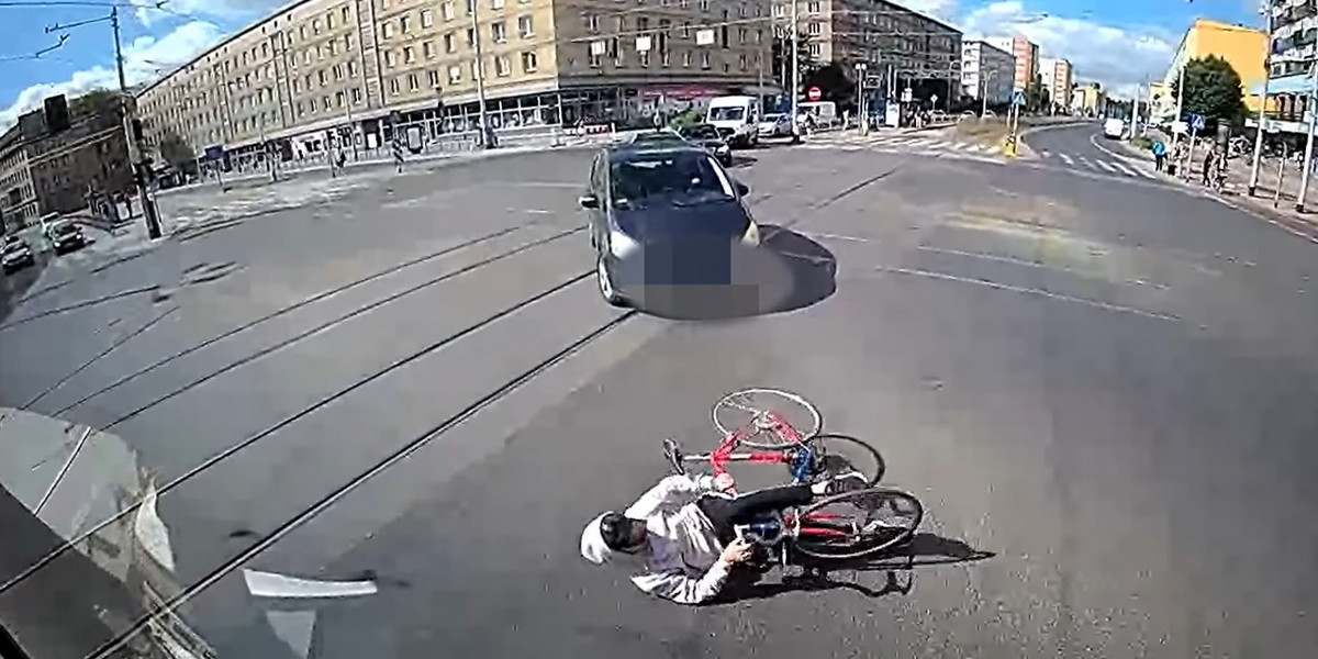 Rowerzysta upadł na środku skrzyżowania między dwoma pasami ruchu — tuż przed maską pojazdu komunikacji miejskiej i auta osobowego. 