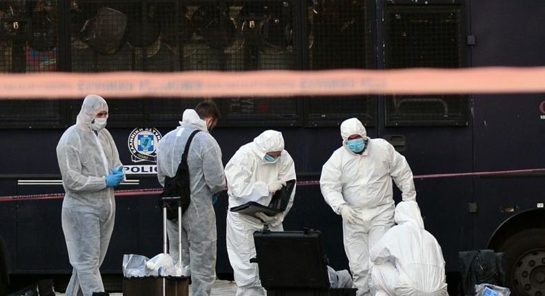 Police officers examine the entrance to the French embassy in central Athens, after two motorcyclists threw a hand granade and injured the guard, early on November 10, 2016