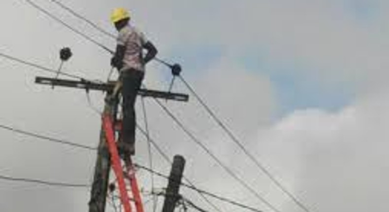 A man standing against a ladder on an electricity pole