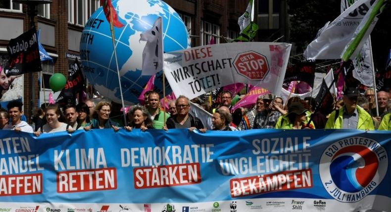 Demonstrators march behind an anti G-20 banner during a demonstration called by several NGOs ahead of the G20 summit in Hamburg on July 2, 2017