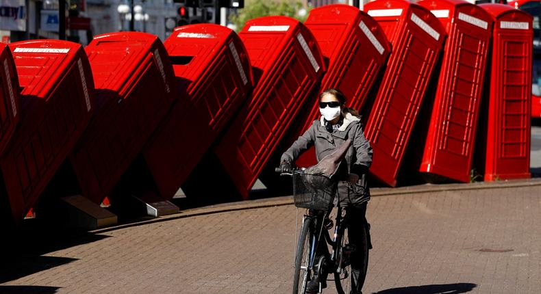 FILE PHOTO: A person is seen riding a bicycle wearing a protective face mask beside an art installation called Out of Order while the spread of the coronavirus disease (COVID-19) continues, London, Britain, April 20, 2020. REUTERS/Peter Nicholls