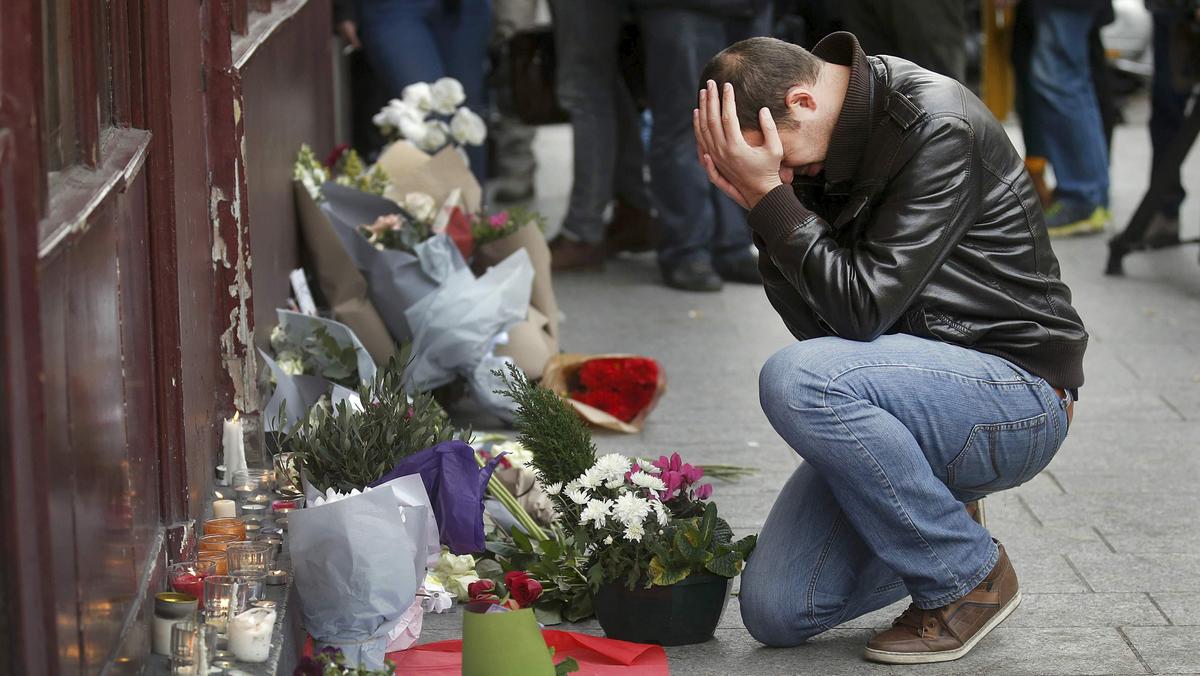 A man pays his respect outside the Le Carillon restaurant the morning after a series of deadly attacks in Paris