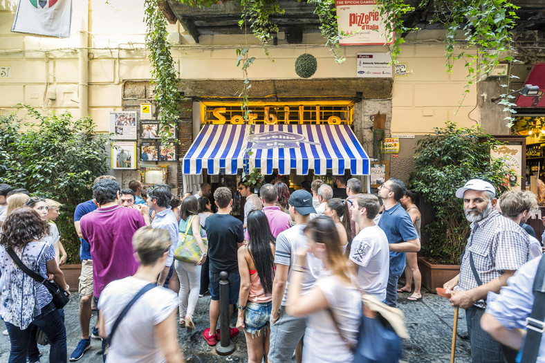 Ludzie czekający na swoją kolej, żeby wejść do pizzerii w Neapolu