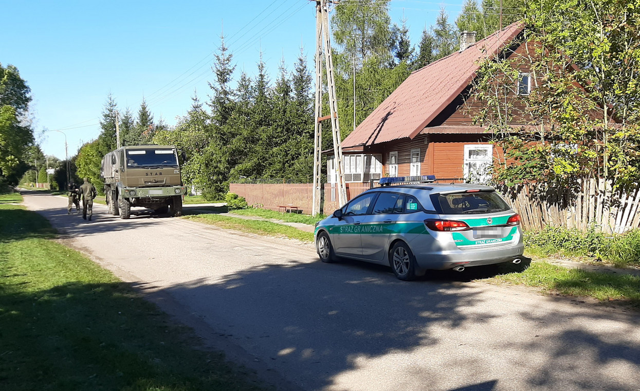 Samochody Straży Granicznej i wojska opuszczają wieś Szymki po interwencji. 