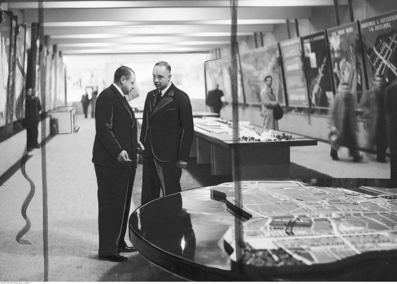 Wystawa "Warszawa wczoraj, dziś i jutro" w Muzeum Narodowym w Warszawie. Prezydent Warszawy Stefan Starzyński (z lewej) rozmawia z naczelnikiem Wydziału Regulacji inżynierem Różańskim. W tle widoczne ekspozycje wystawy