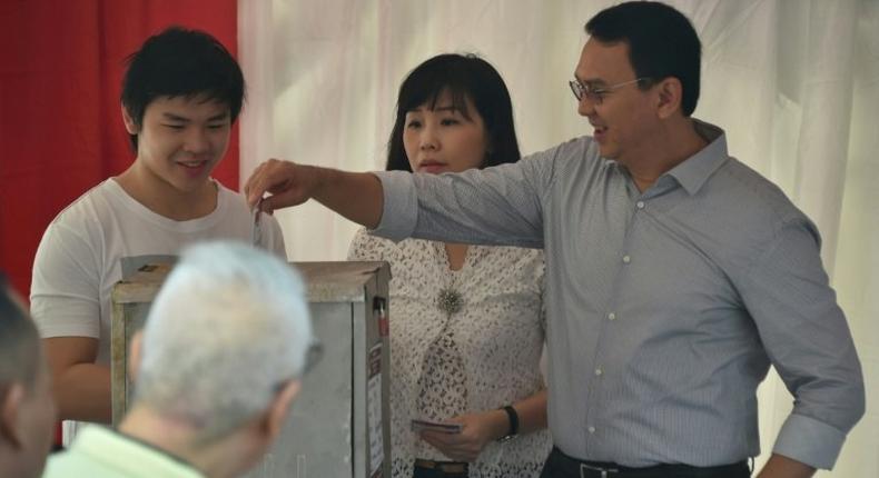 Incumbent Jakarta governor Basuki Tjahaja Purnama casts his ballot next to his wife Veronica and son Nicholas at a polling station on April 19, 2017