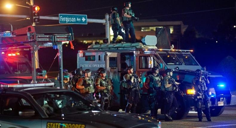 St. Louis County Police officers, outfitted in tactical equipment, monitor the situation in Ferguson, Missouri on August 10, 2015