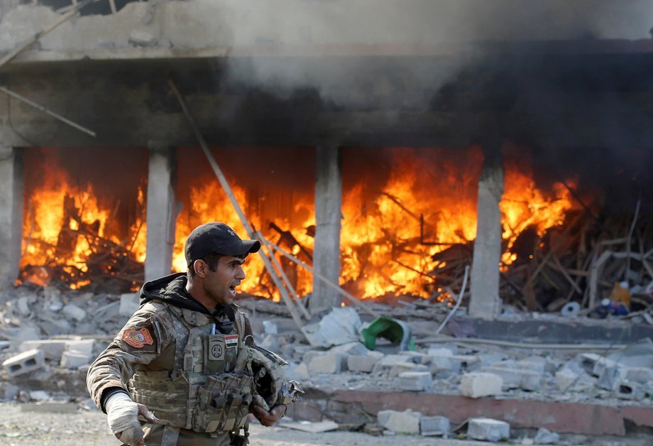 An Iraqi special-forces soldier standing in front of a burning house after an ISIS suicide car-bomb attack in Mosul on November 19.