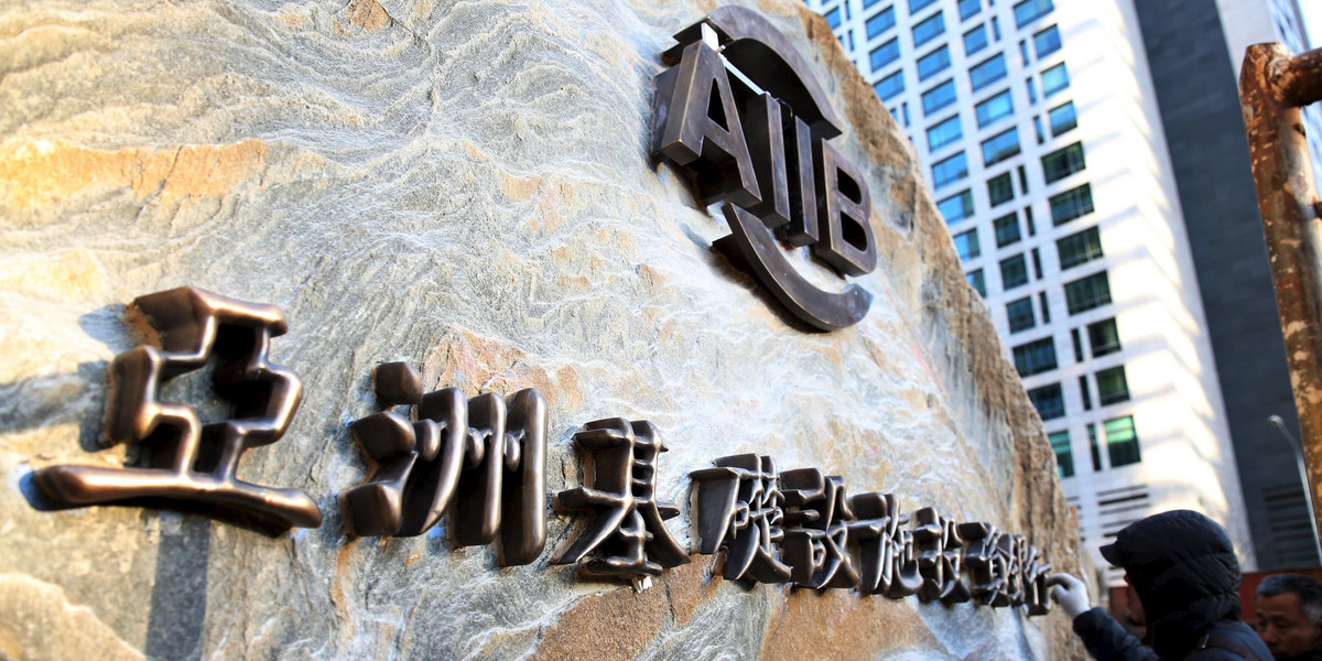 A worker installs a sign of Asian Infrastructure Investment Bank at its headquarters ahead of its opening ceremony in Beijing