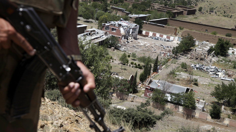 Zołnierz armii pakistańskiej stoi na posterunku obserwacyjnym nad gruzami rzekomej kryjówki talibów