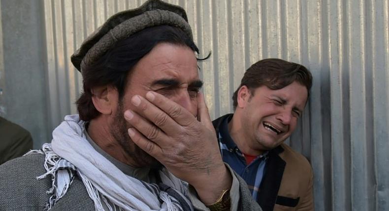 Afghan men weep for their relatives outside the main military hospital in Kabul, on March 8, 2017