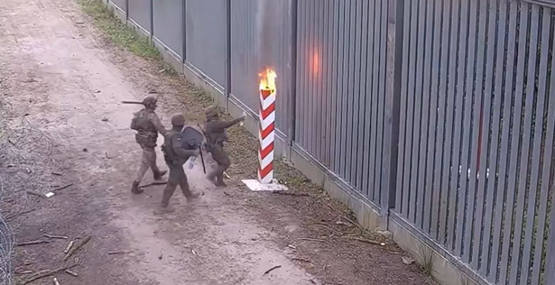 Funkcjonariusze Straży Granicznej gaszą podpalony ze strony białoruskiej słup graniczny