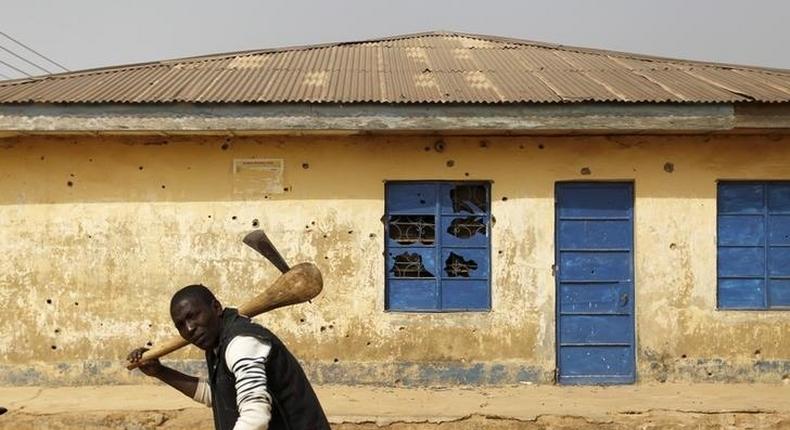 A man carrying an axe walks past a house marked with bullet holes in Gyallesu district after recent clashes between Shi'ites and the army in Zaria, Kaduna state, Nigeria, February 3, 2016. REUTERS/Afolabi Sotunde