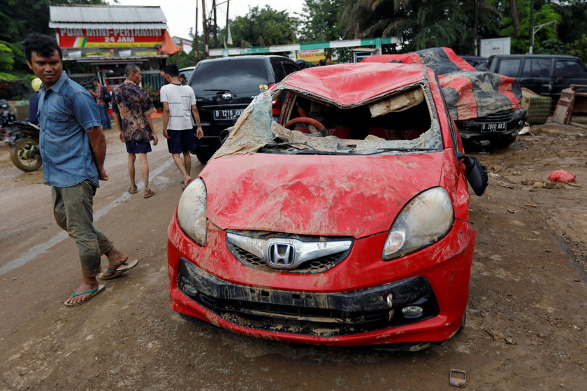 A man looks at a car damaged by the flood at a residential area in Bekasi