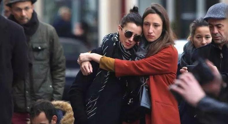 Women comfort each other as they stand in front of the Carillon cafe, in Paris, on Nov. 14, 2015.