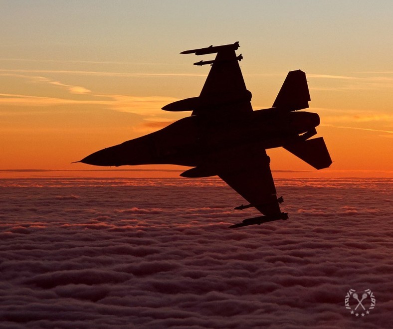 Polski samolot F-16 Block 52+ na tle zachodzącego słońca. Widczone pociski na końcówkach skrzydeł to AIM-120. Bliżej kokpitu znajdują się AIM-9X.