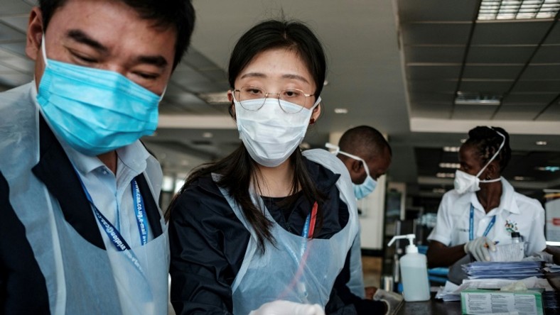 Chinese embassy officials help screen incoming passengers for the new coronavirus as they arrive at Entebbe Airport in Uganda on March 3, 2020