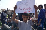 A refugee boy holds up placard reading Sorry for Brussels as refugees and migrants take part in a 