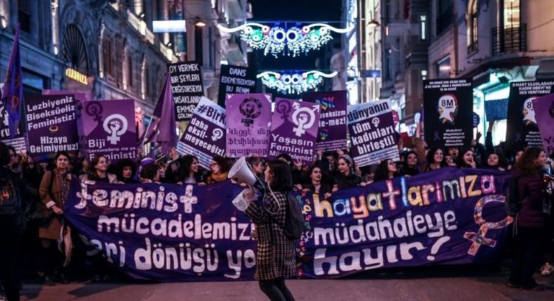 People hold signs as they march down Istiklal Avenue during a feminist night march to mark International Women's Day in Istanbul on March 8, 2017