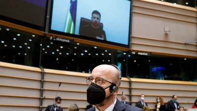 Przewodniczący Rady Europejskiej Charles Michel (z przodu) słucha, jak prezydent Ukrainy Wołodymyr Zełenski (na ekranie) przemawia do członków Parlamentu Europejskiego za pośrednictwem wideokonferencji. Nadzwyczajna sesja plenarna poświęcona rosyjskiej agresji na Ukrainę w Parlamencie Europejskim w Brukseli, 1 marca 2022 r.