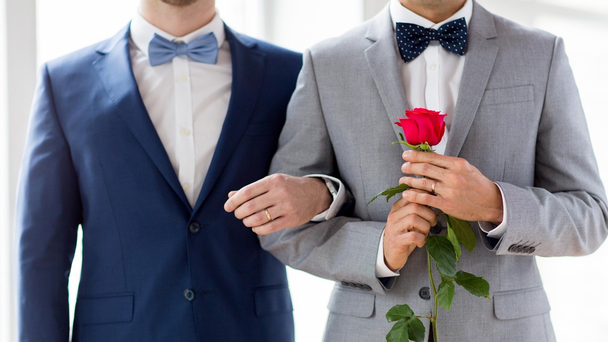 close up of happy male gay couple holding hands