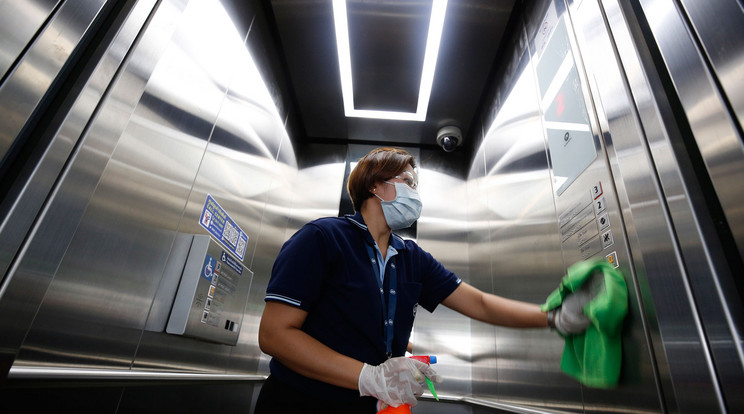 Személyfelvonó falát fertőtleníti egy takarítónő a koronavírus okozta járvány elleni óvintézkedésként egy bangkoki vasútállomáson / Fotó: MTI/EPA/Narong Szangnak