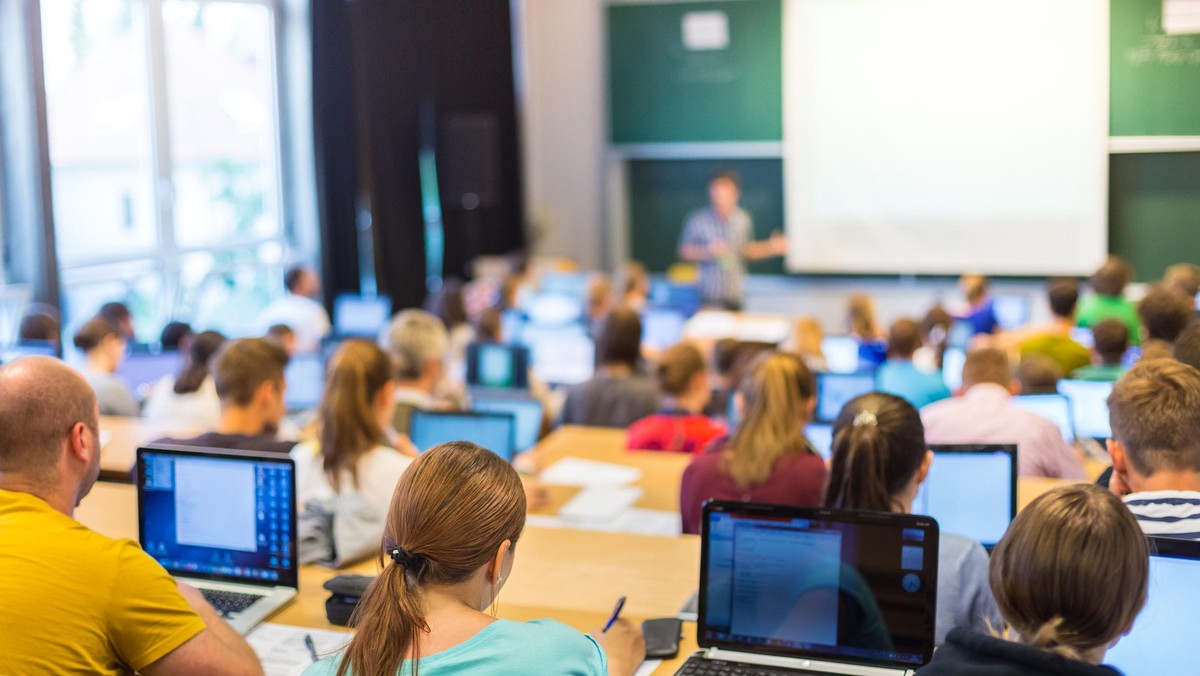 44192156 - rear view of students sitting and listening in lecture hall doing practical tasks on thei