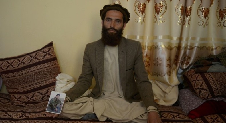 Afghan resident Ahmadullah poses for a photograph on April 24, 2017 with a picture of his brother Shir Mohammad, a soldier killed in a Taliban attack on an army base on the outskirts of Mazar-i- Sharif