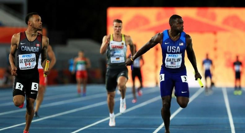 Andre De Grasse (L) of Canada and Justin Gatlin of the US cross the finish line during the IAAF/BTC World Relays Bahamas 2017, at Thomas Robinson Stadium in Nassau, on April 22