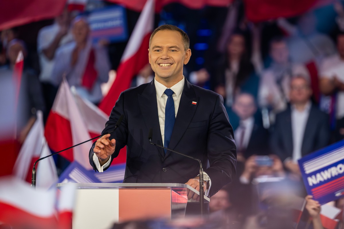 Karol Nawrocki przemawia na tle flag Polski