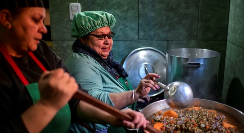 Women serve food at a soup kitchen which feeds at least 200 people hit hard by the economic crisis