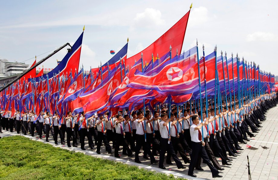 North Koreans holding national flags march during a parade to mark the 60th anniversary of the signing of a truce in the 1950-1953 Korean War at Kim Il-sung Square, in Pyongyang July 27, 2013.