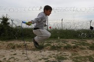 A boy jumps a rope next to a border fence at a makeshift camp for refugees and migrants at the Greek-Macedonian border near the village of Idomeni