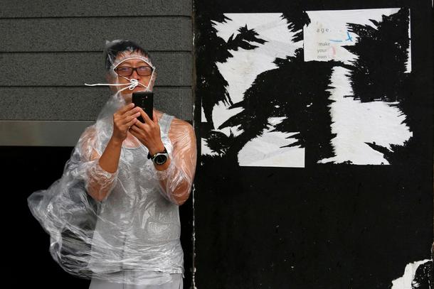 A man uses a smartphone under strong winds near a waterfront as Typhoon Haima approaches in Hong Kon