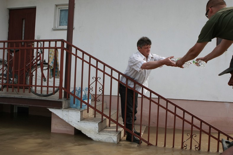 Świniary, 10.06.2010. Ratownik podaje gospodarzowi zalanego gospodarstwa butelki z wodą, w Świniarach 10 bm.  (pp/kkk) PAP/Piotr Piotrowski