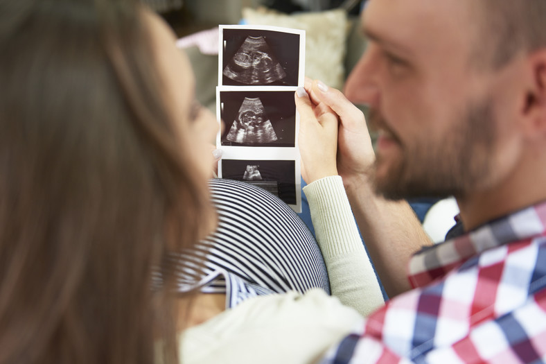 Mąż i żona patrzą z radością na zdjęcie USG