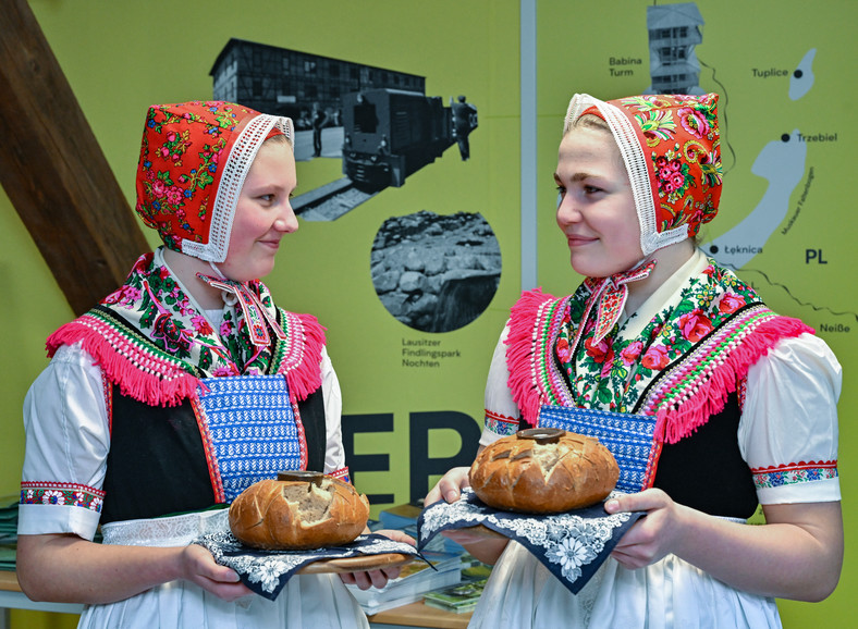 Niemki w tradycyjnych strojach i z chlebem podczas państwowej uroczystości.