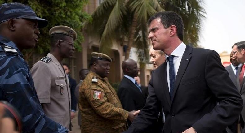 French Prime Minister Manuel Valls shakes hands with head of rapid intervention unit Commander Evrard Somda in front of Cappuccino cafe, the site of an Al Qaeda attack that killed 30 in January in Ouagadougou, Burkina Faso, February 20, 2016. REUTERS/Nabila El Hadad