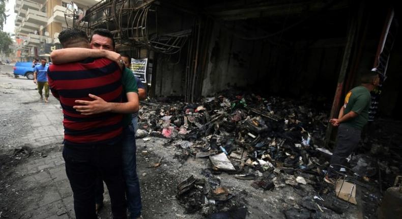 Iraqi men hug on July 4, 2016 at the site of a suicide-bombing attack which took place in Baghdad's Karrada neighbourhood