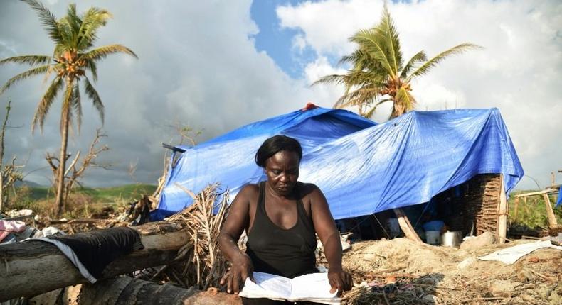 A woman sits close to her house damaged by Hurricane Matthew in the village of Labeyi, in southwestern Haiti, on November 3, 2016