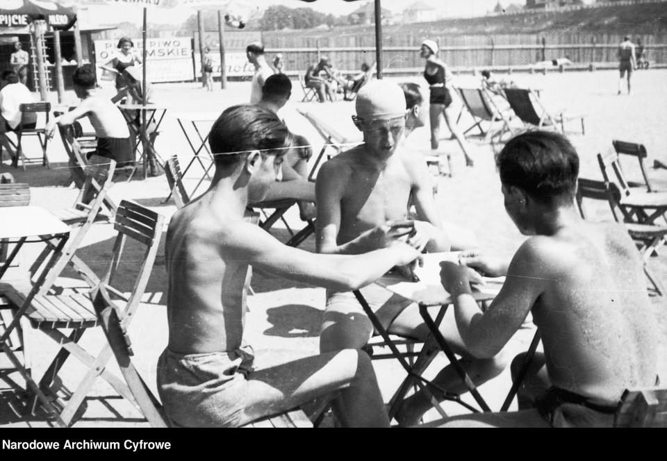 Wakacje w przedwojennej Polsce (na zdjęciu: plażowicze podczas gry w karty przy stoliku w 1931 r.)