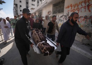 Palestinci nose telo osobe poginule u izraelskim vazdušnim napadima u petak, usmerenim na Iza al Dina al Hadada, vođu Hamasa