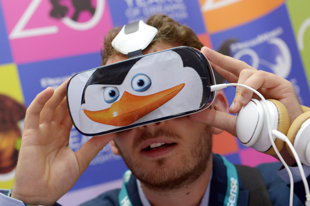 Koreańska firma Samsung zaprezentowała po raz pierwszy oficjalnie gogle Gear VR, sprzęt dla miłośników smartfonowych gier i filmów 3D. Sterowanie interfejsem możliwe jest za pośrednictwem panelu dotykowego znajdującego się na obudowie gogli. Jednak jest też inny sposób komunikacji z virtualną rzeczywistością. Gear VR reaguje także na polecenia głosowe. Gogle Samsung Gear VR mają trafić do sprzedaży jeszcze w tym roku. Na zdjęciu widać jak uczestnik targów testuje gogle Samsunga Gear VR. fot. EPA/RAINER JENSEN